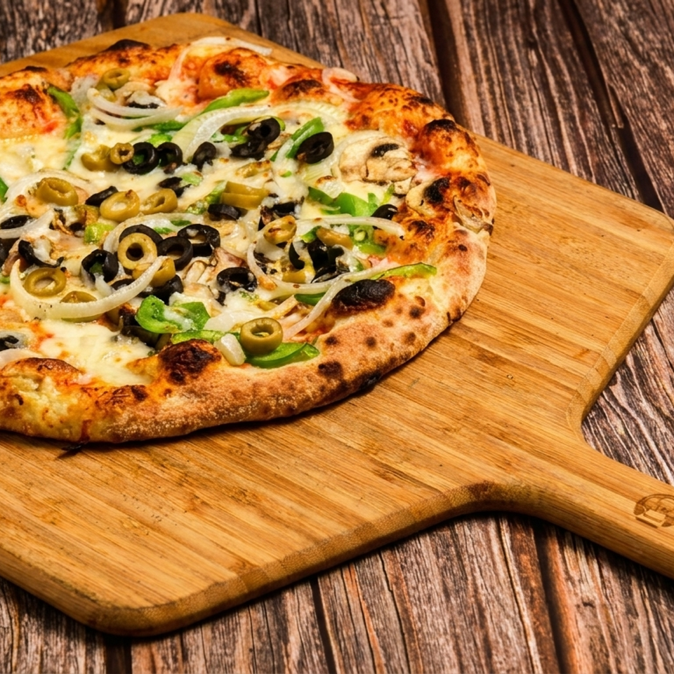 A freshly baked pizza with olives, onions, and peppers on a wooden peel from Chef Pomodoro.